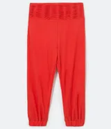 Pantalón jogger color naranja, de tiro alto con cintura ancha fruncida y elástica, bolsillos traseros y botamangas con elástico.