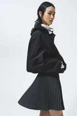 Minifalda plisada de corte evasé, en color negro, con cintura elástica de ribete oscuro y sutiles líneas contrastantes.