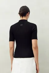 Top negro de manga corta tejido con textura acanalada, cuello alto y terminaciones onduladas.