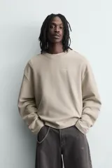 Sudadera de corte boxy fit confeccionada en tejido de mezcla de algodón, con cuello redondo y mangas largas. Presenta un diseño minimalista con texto estampado a contraste en el pecho y efecto lavado.