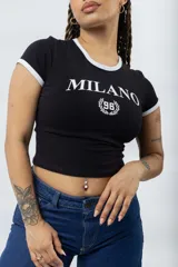 Remera ajustada de manga corta color marrón oscuro, con cuello redondo y ribetes blancos en el cuello y mangas. Presenta un estampado frontal en blanco con el texto "MILANO" y un escudo con el número "96".