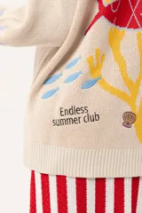 Saco tipo cárdigan oversize de tejido de punto color beige, con diseño inspirado en el universo marino que incluye ilustraciones de corales, peces y estrellas de mar. Presenta detalles de galón picot en color rojo en los bordes y puños, cierre frontal con botones rojos y un corte holgado.