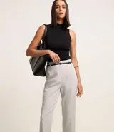 Pantalón zanahoria de vestir color gris claro, con cintura alta, cinturón con hebilla metálica y corte holgado en las caderas que se estrecha en las piernas.