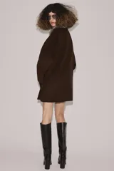 Abrigo confeccionado en hilatura con lana, de corte recto y diseño minimalista. Presenta cuello solapa con aplicación de pelo sintético desmontable, cierre frontal con botones y bolsillos de plastrón en el delantero.
