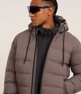 Campera puffer deportiva Get Over, color negro, con capucha, cierre frontal por cremallera y puños elásticos. Diseño acolchado sin costuras visibles.