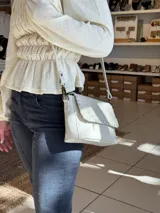 Blusa color manteca con diseño de frunces elásticos en el frente y la espalda, mangas largas abullonadas y terminación con volado en la cintura.
