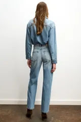 Jeans celeste de tiro alto, corte recto y largo, con cinco bolsillos y cierre frontal con cremallera y botón.