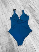 Malla entera plus size con diseño combinado, parte inferior negra y parte superior con estampado floral en tonos amarillos, rojos y celestes, con escote en V cruzado.