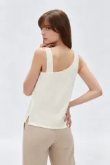 Musculosa blanca sin mangas de viscosa, con cuello asimétrico y detalles bordados en tono sobre tono.