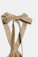 Top de cuello halter con tiras cruzadas para atar al cuello, hombros descubiertos y bajo asimétrico con caída drapeada y textura rústica con estampado sutil.