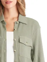 Sobrecamisa de textura tipo waffle en color blanco, con cuello camisero, cierre frontal con botones y dos bolsillos delanteros con solapa.