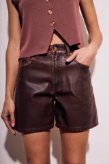 Short marrón de cuero sintético, tiro medio y corte recto.