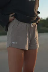 Short color beige con cintura elástica ajustable con cordón, bolsillos laterales y logo estampado en la pierna izquierda.