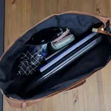 Bolso tipo hobo de eco cuero con textura símil gamuza color marrón rojizo. Presenta detalles de cuero liso color caramelo en la base y tiras ajustables en los laterales.