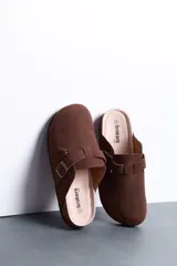 Sandalias estilo zueco de hombre, color marrón, con capellada cerrada, tira con hebilla ajustable lateral y suela de corcho y goma.