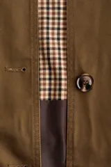 Chaqueta de sarga color marrón con cuello de pana de algodón oscura, capa decorativa desmontable, cierre de botones delanteros, bolsillos con solapa y cordón interior para ajustar la cintura.
