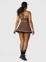 Falda skort deportiva color chocolate con short integrado, confeccionada en tejido técnico de secado rápido con borde inferior en contraste blanco.