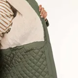 Parka de color verde militar con acabado repelente al agua, diseño de corte holgado, capucha integrada y forro interior de efecto borreguito. Cuenta con cierre frontal de cremallera y botones a presión, además de bolsillos frontales con solapa.