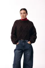 Sweater de punto grueso color chocolate, con diseño de rombos en relieve, cuello redondo y mangas amplias con puños ajustados.