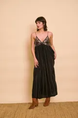 Vestido largo negro con tirantes finos, escote en V y el busto bordado con lentejuelas. Presenta líneas de bordados verticales a lo largo de la falda fluida.