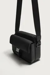 Bandolera de acabado engomado negro con compartimento principal con cierre, bolsillo interior con cierre y bolsillo frontal con solapa y hebilla metálica de liberación rápida. Cuenta con asa de hombro ajustable y extraíble.