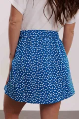 Minifalda azul con estampado de flores blancas, corte evasé y lazo lateral ajustable.