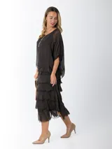 Vestido midi de seda italiana color negro, diseño dos en uno con capa superior de calce amplio, falda con volados y forro interior de algodón elastizado.
