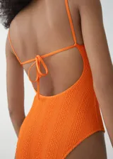 Malla enteriza de color naranja con textura arrugada, escote recto y tirantes finos.