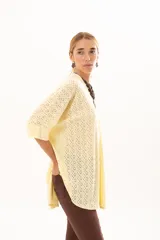 Camisa de corte oversize y mangas murciélago, confeccionada en tela con perforaciones tipo broderie. Presenta cuello mao, cierre frontal con botones y un diseño holgado y fluido.