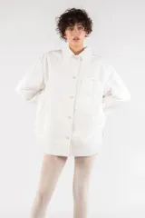 Camisa blanca oversize de nailon arrugado, con cuello clásico, cierre frontal con botones, manga larga raglán, puños abotonados, bolsillo utilitario en el pecho, bolsillos laterales y canesú abotonado en la espalda.