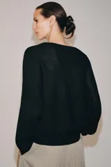 Jersey de punto negro con escote en V pronunciado, mangas largas con sisa caída y puños y dobladillo acanalados.