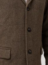 Chaqueta tipo blazer para hombre, confeccionada en mezcla de lana con diseño de espiga en tonos marrones. Presenta cierre frontal de tres botones, solapas clásicas, bolsillos laterales con solapa y un bolsillo en el pecho. Cuenta con un diseño estructurado y elegante.