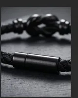 Pulsera de diseño trenzado en color negro, confeccionada en cuerina con un nudo metálico central y cierre magnético.