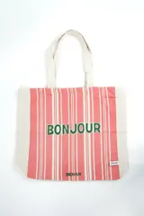 Bolso tipo tote bag de color crudo con estampado de flores celestes y centros azul oscuro. Cuenta con doble asa de hombro en tono crudo y etiqueta con la marca en el frente.