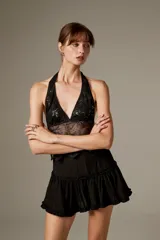 Top halter negro al cuerpo de poliéster, con diseño translúcido, bordado floral y detalles de lentejuelas.
