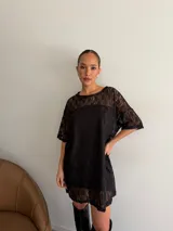 Remerón de encaje negro con mangas cortas y cuello redondo, acompañado de un vestido strapless interior corto en el mismo tono.