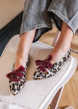 Bailarina de cuero con estampado animal print, decorada con tachuelas plateadas y un lazo desmontable de tela metalizada en color fucsia.