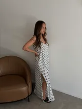 Vestido largo de crepe con estampado de lunares negros sobre fondo blanco. Presenta un diseño de corte holgado con breteles finos y escote redondeado.