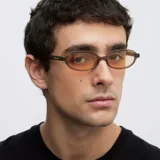 Lentes de sol con montura ovalada de color camel y cristales amarillos. Presentan un diseño estilizado y ligero, con protección UV400.