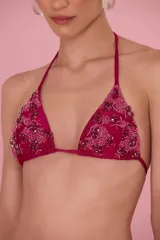 Top de bikini estilo triángulo color fucsia, con tirantes finos para anudar al cuello y a la espalda. Las copas están decoradas con un bordado artesanal de cuentas y pedrería en tonos magenta y borravino.