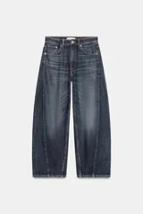 Jeans de tiro medio con diseño baggy barrel, cinco bolsillos y costuras laterales torcidas. Cierre frontal con cremallera y botón metálico.