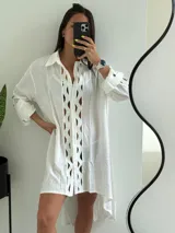 Vestido camisero blanco con aberturas geométricas en el frente, mangas largas con volados y bajo irregular.