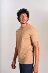 Remera de manga corta con cuello redondo, confeccionada en algodón de color beige. Presenta un pequeño logo bordado de un pingüino en el pecho.