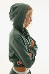 Campera cropped color verde militar, con capucha ajustable con cordón, cierre frontal, hombros caídos y puños y bajo acanalados.