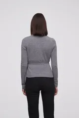 Saco tipo cardigan cruzado de punto, color gris melange, con escote en V profundo, mangas largas y lazo lateral para ajustar a la cintura.