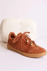 Zapatillas bajas color marrón con cordones y charms dorados.