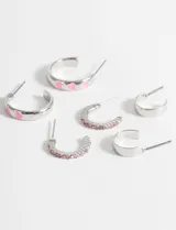 Set de tres pares de aros plateados tipo argolla. Un par liso, un par con corazones rosas y un par con strass rosas.