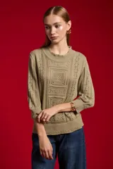 Sweater acrílico en tono natural, de corte holgado, con cuello a la base decorado con sutiles volados, mangas 3/4 y diseño tejido con motivos geométricos calados en el frente.