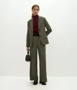 Pantalón de sastrería modelo wide leg color verde militar, confeccionado en crepé. Presenta pliegues delanteros, cintura con trabillas e incluye un cinturón de gamuza a tono.