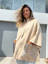 Saco tejido de punto en color crudo, con diseño holgado, mangas tres cuartos y bolsillos frontales grandes confeccionados en cuero metalizado plateado.